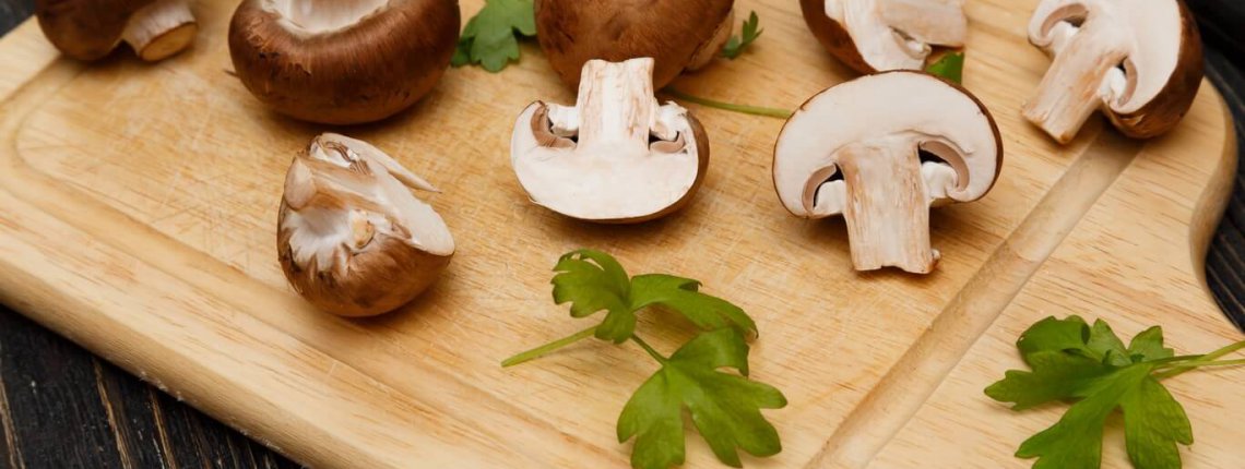 Cutted royal raw champignons with green on wooden board